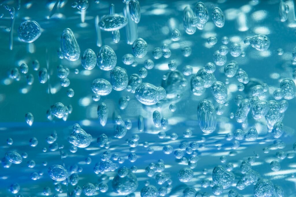 Close-up of blue water bubbles floating in a clear liquid, creating an abstract and calming pattern.